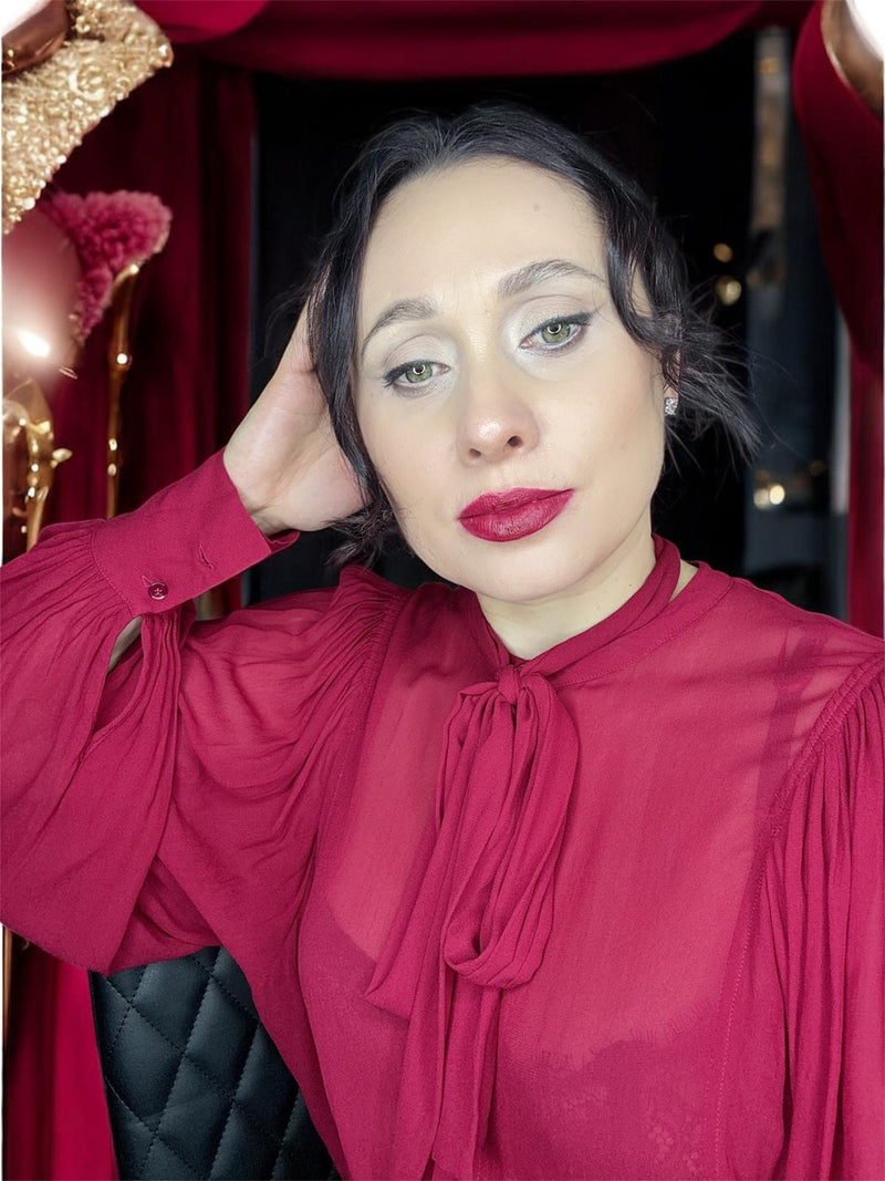 Woman wearing a red blouse with a bow tie in a festive setting.