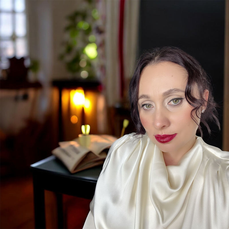 Woman with dark hair and makeup wearing a white outfit 